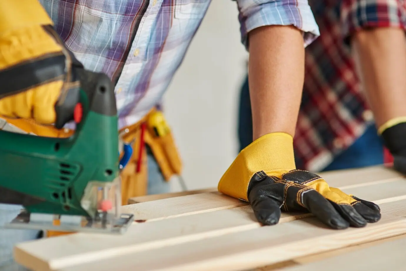 Nahaufnahme eines erfahrenen Tischlers und seines jüngeren Mitarbeiters.